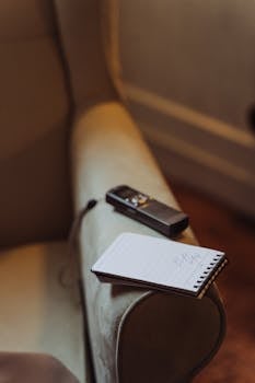 Cozy indoor setting with a notepad and recorder on a chair armrest.