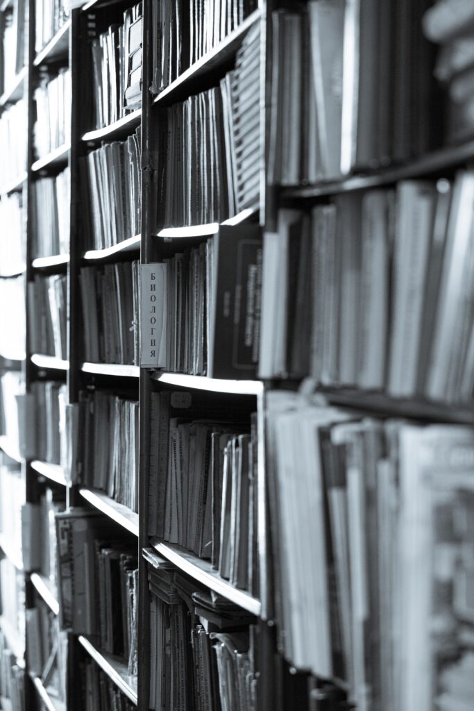 Grayscale view of packed library shelves filled with books in a vertical alignment.